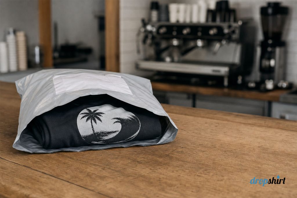 A single folded printed t-shirt in an Australia Post satchel on a cafe counter